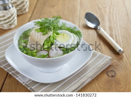 Cold vegetable soup with sorrel and boiled fish on a wooden table