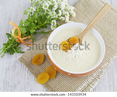 Rice soup with cream and dried apricots in the orange bowl