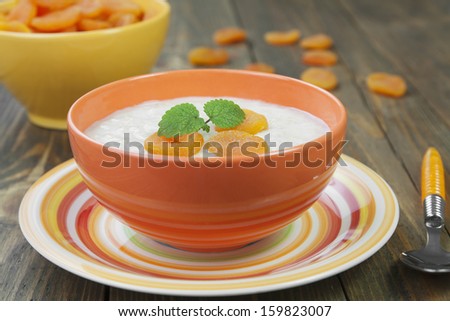 Oatmeal with dried apricots, decorated with mint in orange bowl