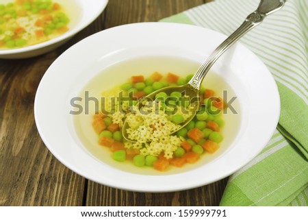 Soup with star shaped noodles, carrots and green peas. Consomme