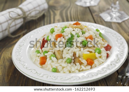 Risotto with chicken and vegetables in the plate on a wooden table