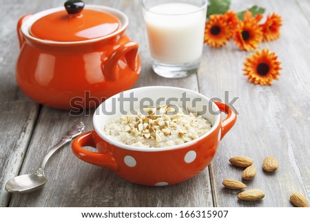 Porridge with almonds in an orange bowl on the table