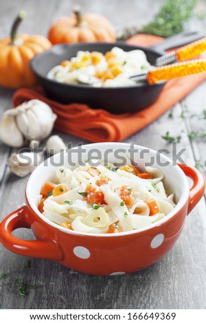 Noodles pasta with pumpkin and parmesan cheese in a orange bowl