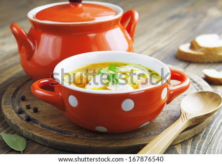 Chicken soup in an orange bowl on the table