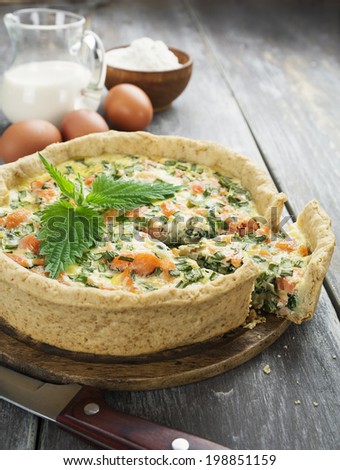 Quiche pie with fish and nettles on the table