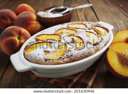 Peach pie in a ceramic pot on the wooden table