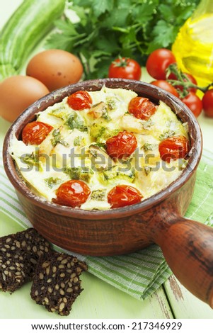 Baked zucchini with chicken, cherry tomatoes and herbs in a ceramic pot