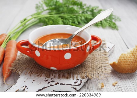 Carrot soup in orange bowl on the table