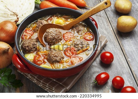 Cabbage soup with meatballs and tomatoes in a bowl