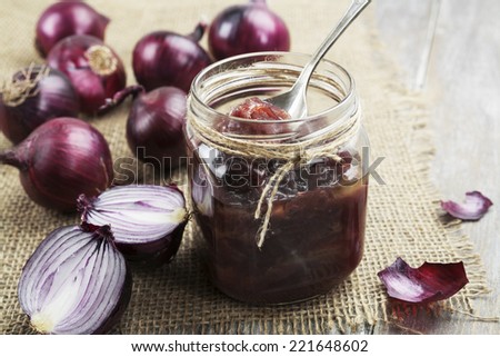Onion jam in a glass jar on a wooden table