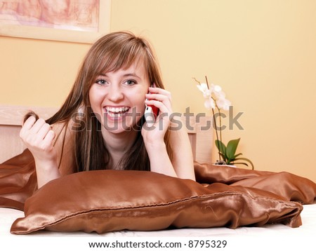 Young woman relaxing in the bedroom/ talking with friend on phone