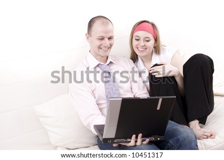 Smiling couple with laptop on a couch. Relax at home.