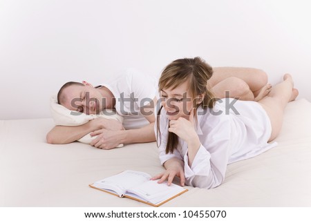 Relax at home. She reading book, he sleeps next to her.