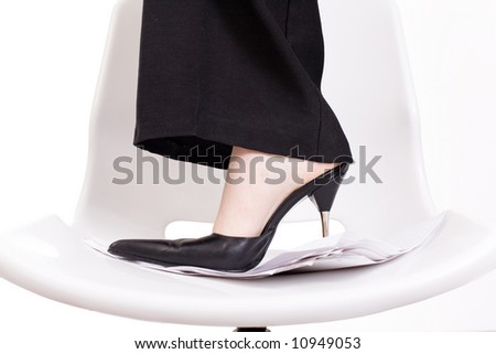 Female foot on office chair and sheet of papers / businesswoman dressed in black suit / copyspace