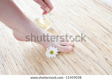 Foot care -Spa and wellness scene - Feet and oil on the bamboo mat