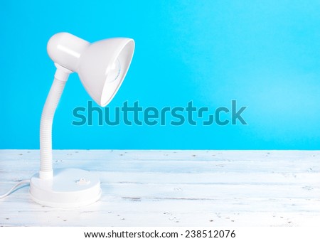 White lamp on white wood desk, blue background