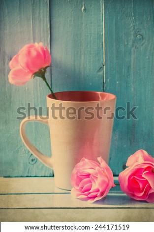 Vintage still life,mug with pink roses on blue wood background