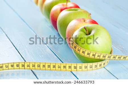 Apples with tape measure on blue wood background, lose weight concept