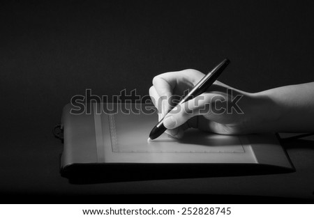Hand drawing on design tablet, black and white low key photo
