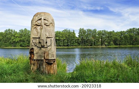 Landscape with a lake and a smiling wooden sculpture