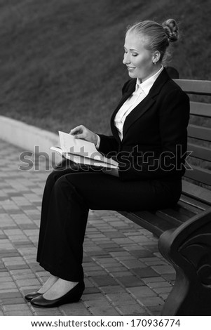 the business woman in strict clothes with a notebook sits on a shop one.
