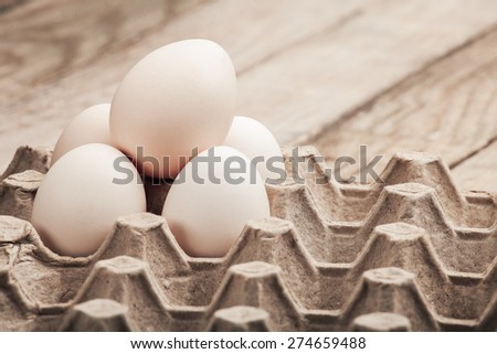 Eggs in a paper tray on a wooden table from old boards.