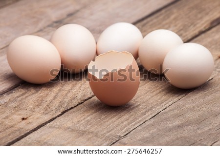 The eggs which are laid out on a wooden table from old boards with the broken egg in the foreground, nobody.