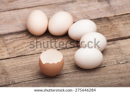 The eggs, the top view which are laid out by a half moon on a wooden table from old boards with the broken egg in the foreground, nobody.