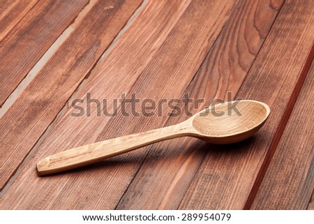 Wooden spoon for cooking of food on a wooden table from boards of brown color.
