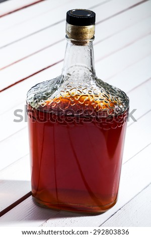 Cognac bottle on a white table from boards, alcoholic drink on a wooden background.
