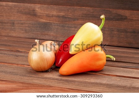 Vegetables on a wooden table from brown boards, vegetarian healthy food, paprika, onions.