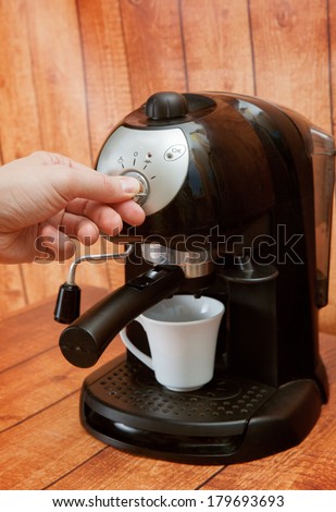 hand turns the switch on the coffeemaker
