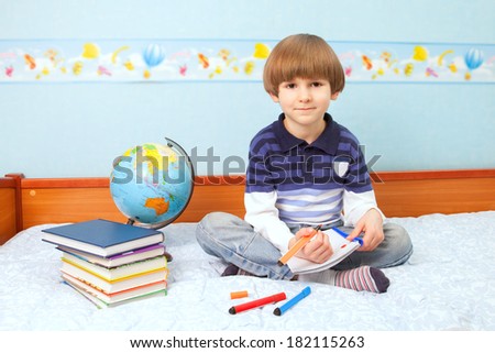 The child with globe, books, notebook and pens