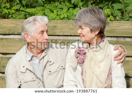 older couple look at each other, sitting on a Park bench