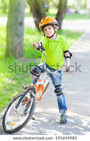 Child rides bike outdoors dressed in a colorful safety helmet