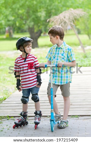 two boys go for a drive on scooter and rollers in the city Park
