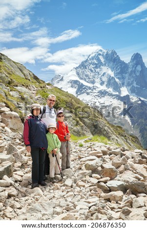 The family from four persons staying on stone trail against mountain summits