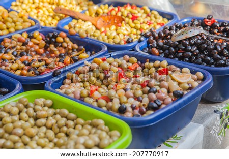 Pickled olives in plastic box on shop counter