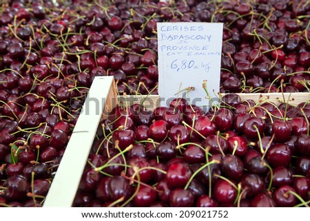 Cherry berries organic food in a wooden box on market counter with price label, France