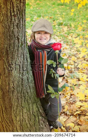 funny boy with rose at the tree in autumn Park
