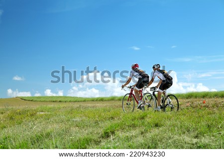 Two Cyclists ride on road in south France in summer sunny day against bright blue sky