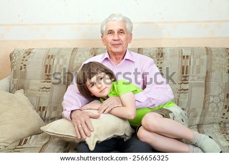 Grandfather with grandson sit on couch together