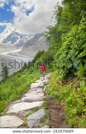A woman runs on mountain trail against glacier
