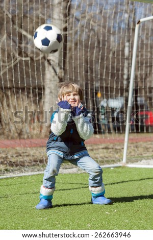 Young goalkeeper tries to catch ball before gate on school stadium