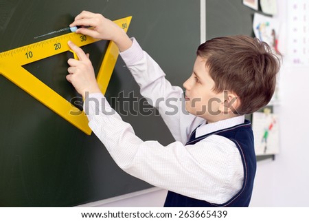 Schoolboy drawing solution of exercise on blackboard