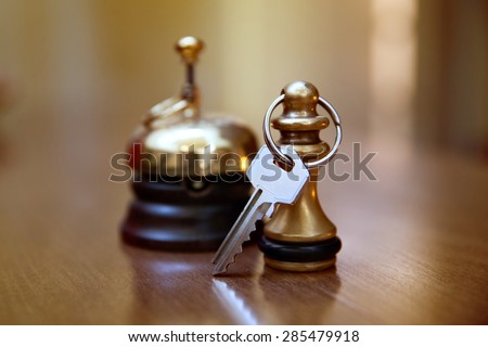 A service bell and room key on the reception desk
