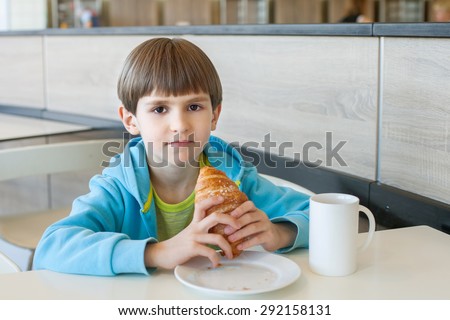 The young boy is eating lunch in the school cafeteria