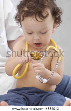 Baby at the doctor, looks at a stethoscope
