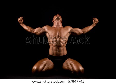 Bodybuilder posing on black background. - stock photo