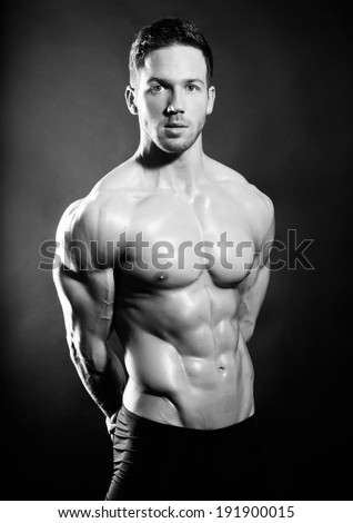 handsome muscular man in black and white on black background